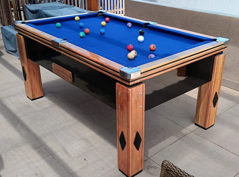 Mesa de sinuca com tecido azul instalada em área de lazer