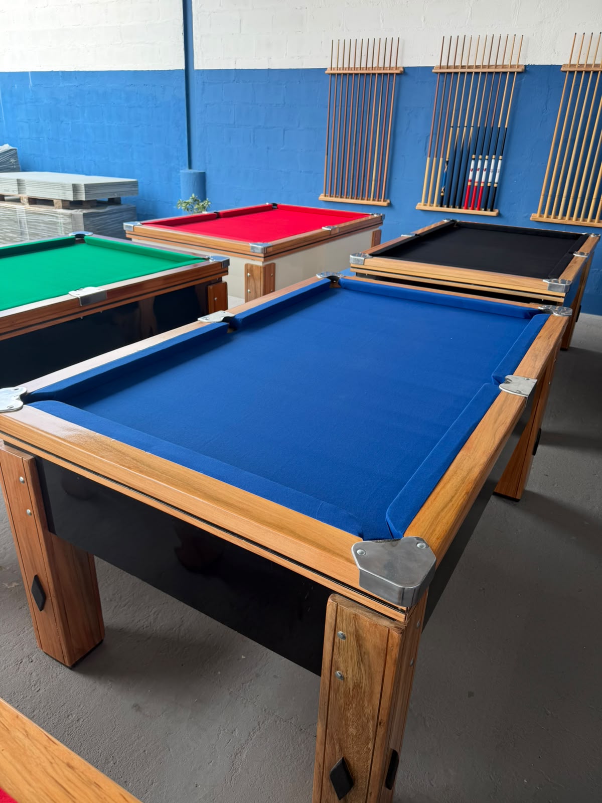 Mesas de sinuca com tecidos azul, verde, vermelho e preto no showroom